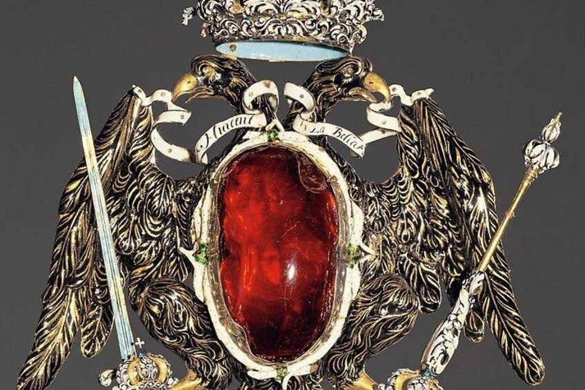 A detailed coat of arms with a central oval, two crossed swords, and a crown. 2
