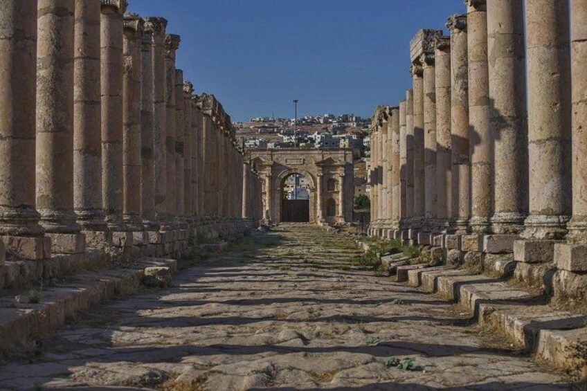 De vieilles colonnes de pierre, une arche centrale et un sentier menant à une ville lointaine. 3