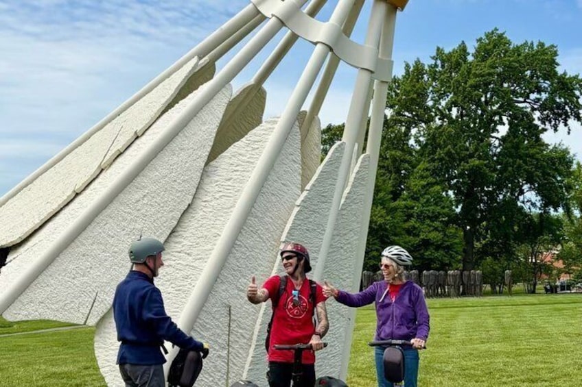 Un grupo de personas cerca de una gran escultura blanca en un parque. 4