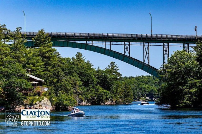 A green bridge over a river, surrounded by trees and a boat. 5