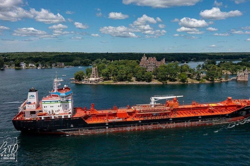 A large cargo ship on a river with a castle and greenery in the background. 2