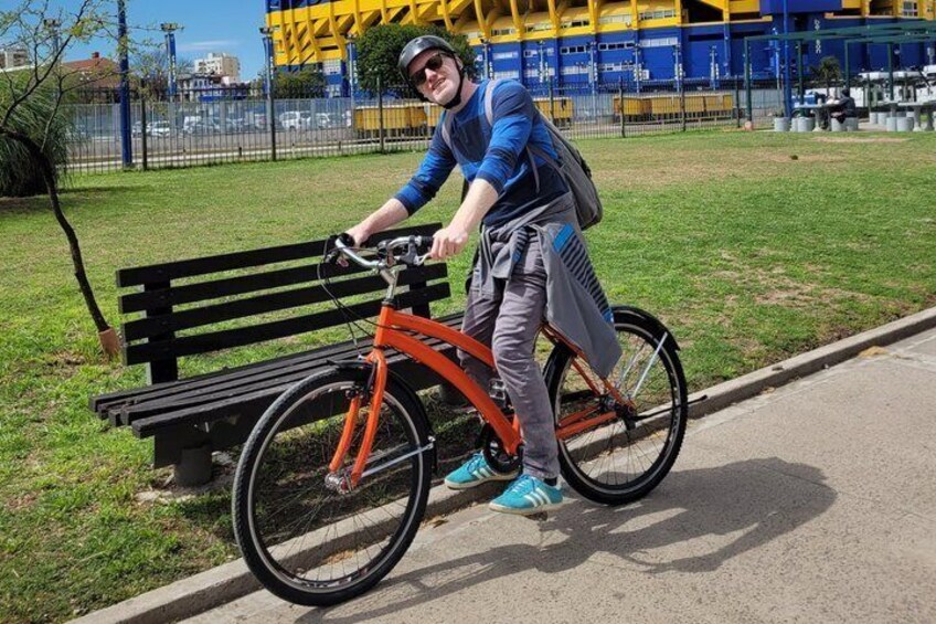 A person riding a bicycle on a paved path next to a bench. 4