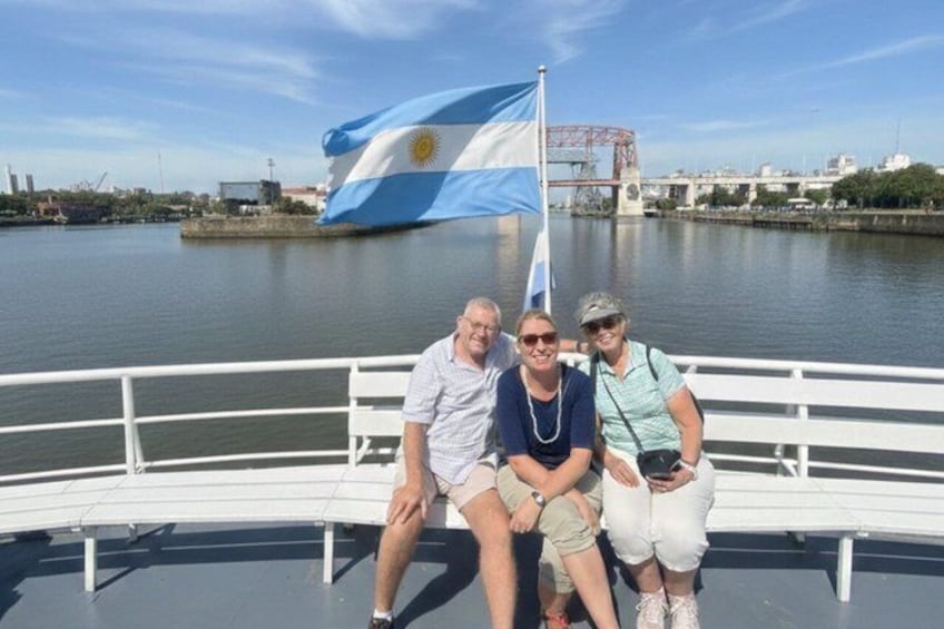 Three people sitting on a boat with a flag in the background. 2
