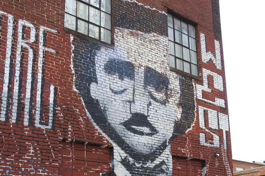 Ein Wandgemälde an einer Ziegelwand zeigt ein großes Gesicht und den Schriftzug 'SURF'. 3