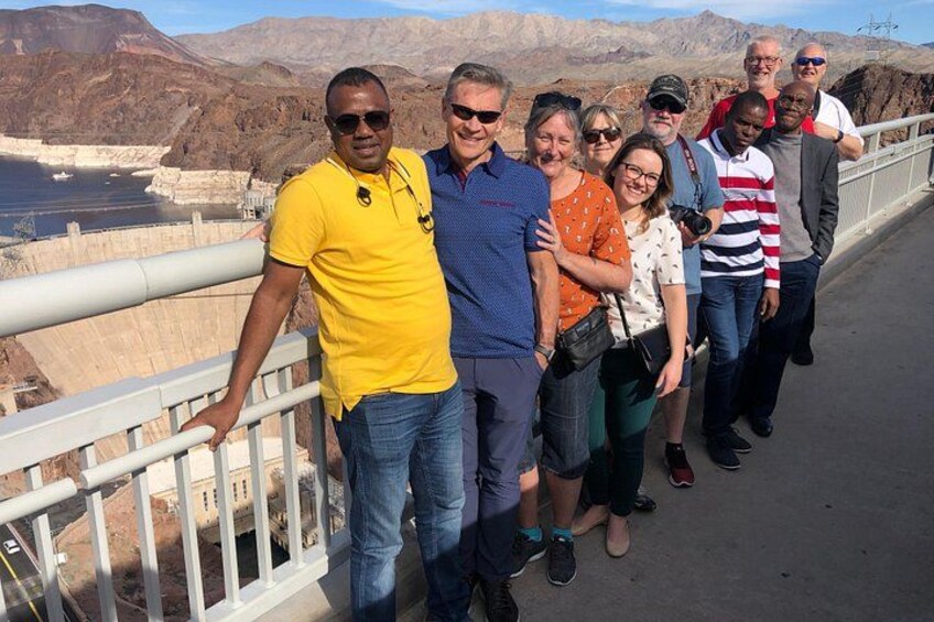 A group of people standing on a bridge with a canyon in the background. 2