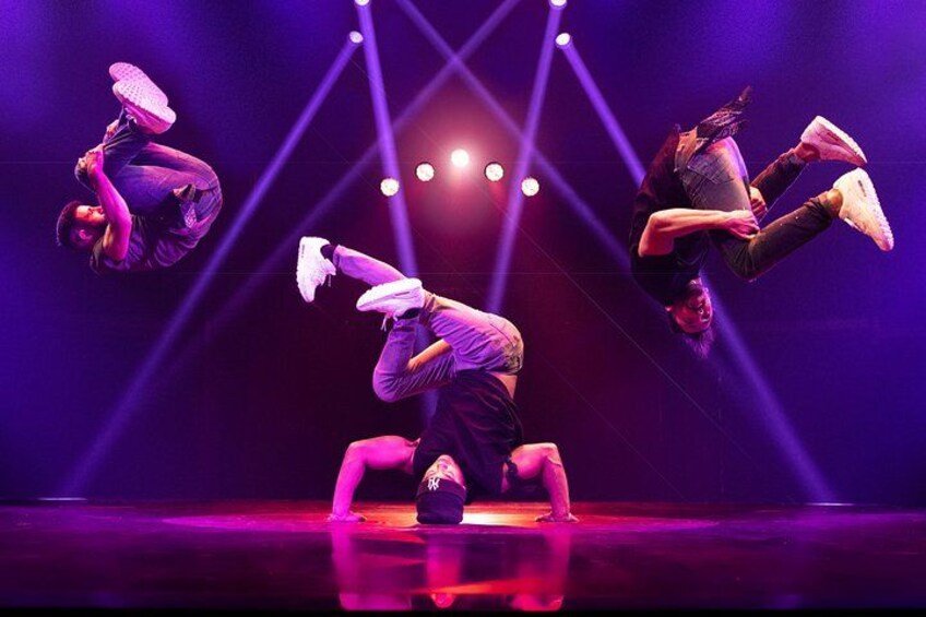 Een podium met drie artiesten in de lucht, verlicht door podiumverlichting. 3