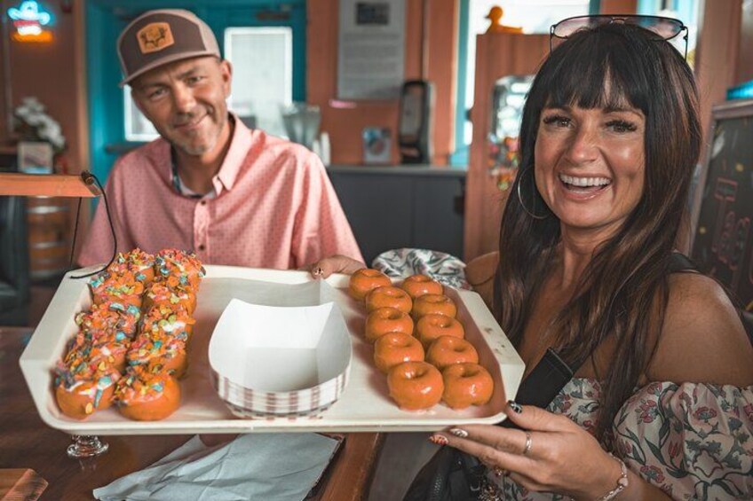 A person holding a tray with donuts and a white box. 3