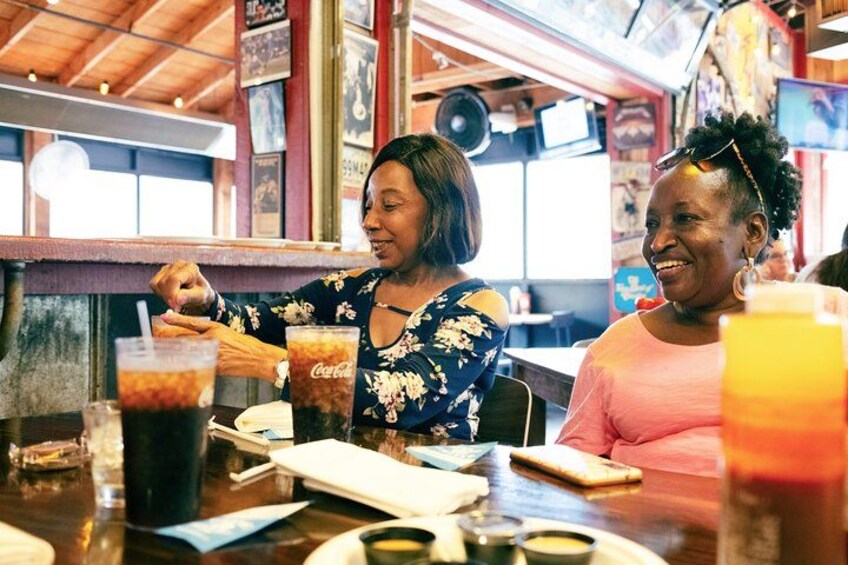 Two people sitting at a table in a restaurant with drinks and a menu. 2