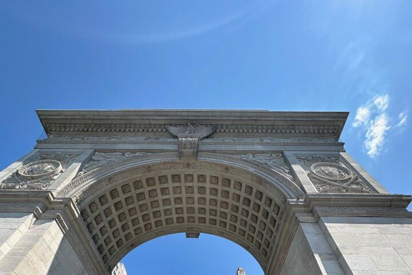 Une grande arche en pierre, ornée de sculptures complexes, se dresse sous un ciel d’un bleu limpide. 2