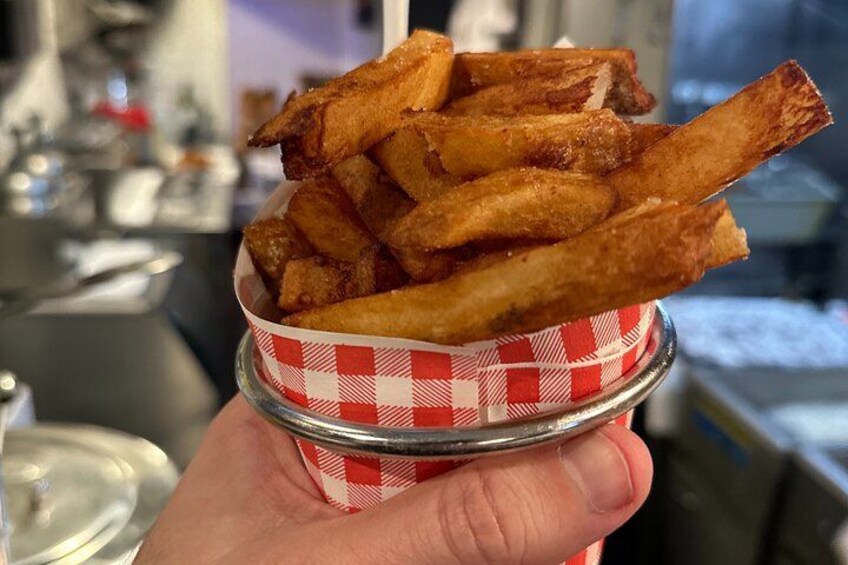 A hand holding a basket of golden-brown fries. 5