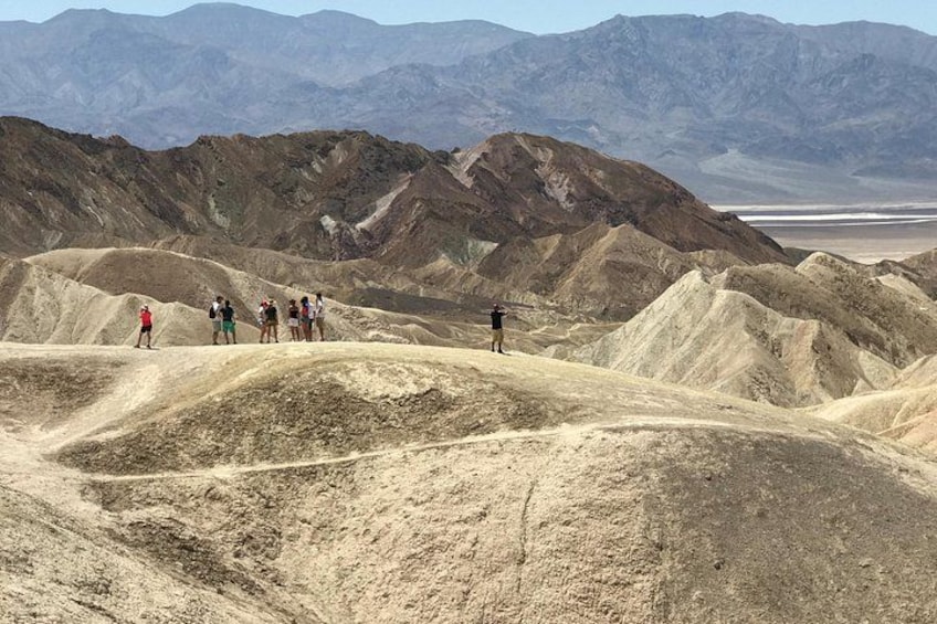 A group of people hiking in a desert landscape with mountains in the background. 3