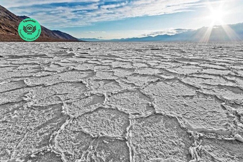 A salt flat with hexagonal patterns, mountains in the background, and a clear sky. 5