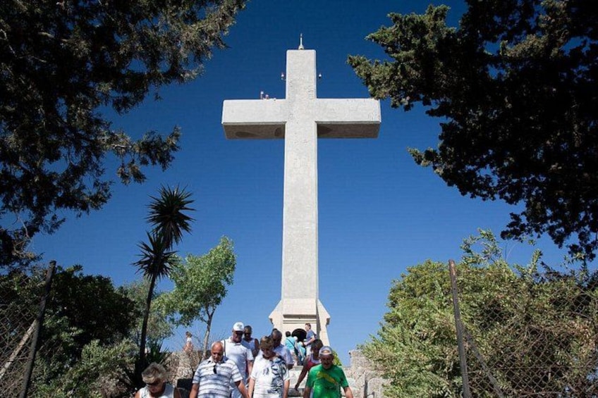 A large cross monument surrounded by trees and a clear blue sky. 4