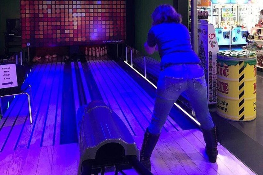 Una bolera con una persona lanzando bolos, una bola de bolos y un lanzador de bolos. 2