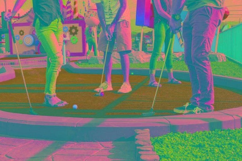 Personas jugando croquet en un campo verde con una valla de madera y un pequeño estanque al fondo. 4