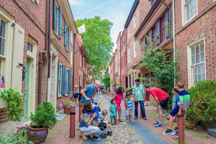 A group of people gathered on a brick street with buildings on either side, some with American flags. 4