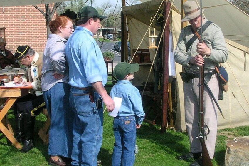 Une scène de reconstitution historique avec des personnes vêtues de costumes d’époque, des tentes et une personne en uniforme. 4