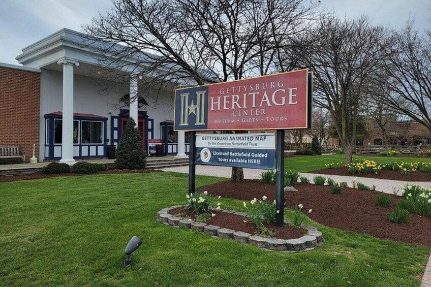A sign for Gettysburg Heritage Center with a brick building in the background. 1