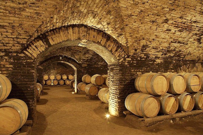 A cellar with brick arches and wooden barrels. 4