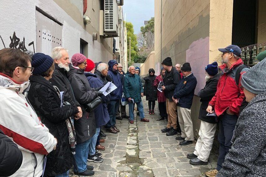 A group of people standing in a narrow alleyway, some holding papers. 5