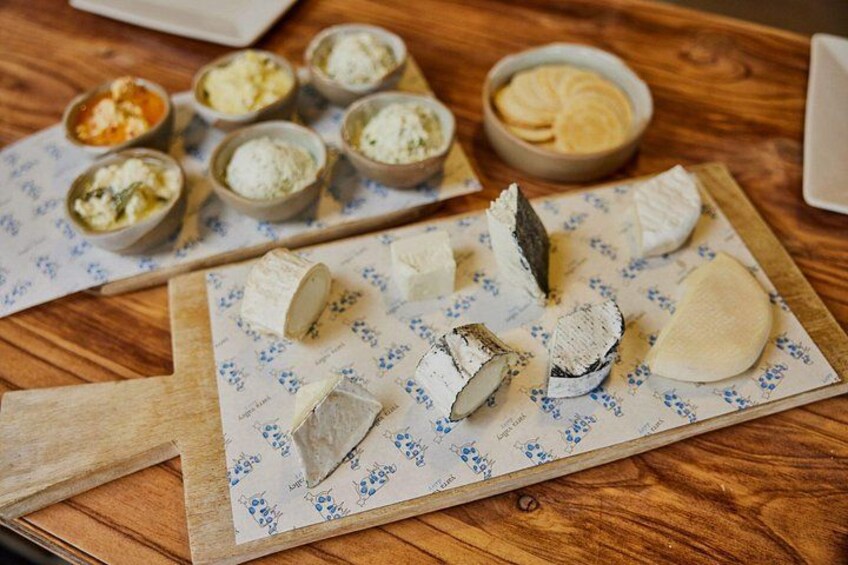 A wooden table with various cheeses and crackers. 2