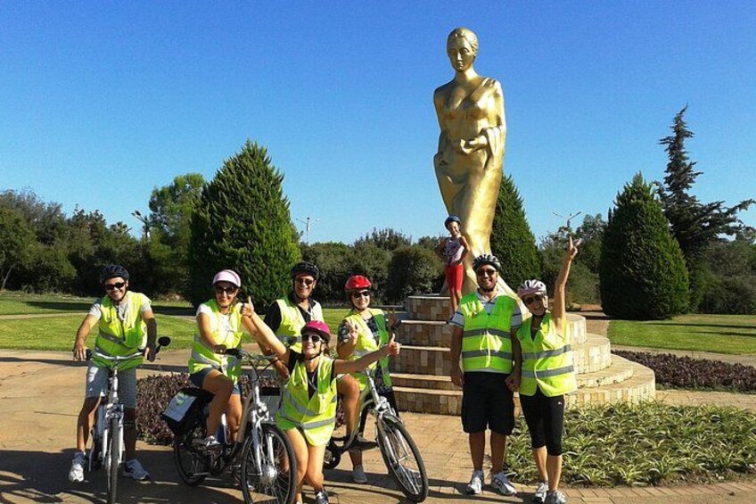 Un gruppo di persone con giubbotti di sicurezza che posano accanto a una grande statua dorata in un parco. 4