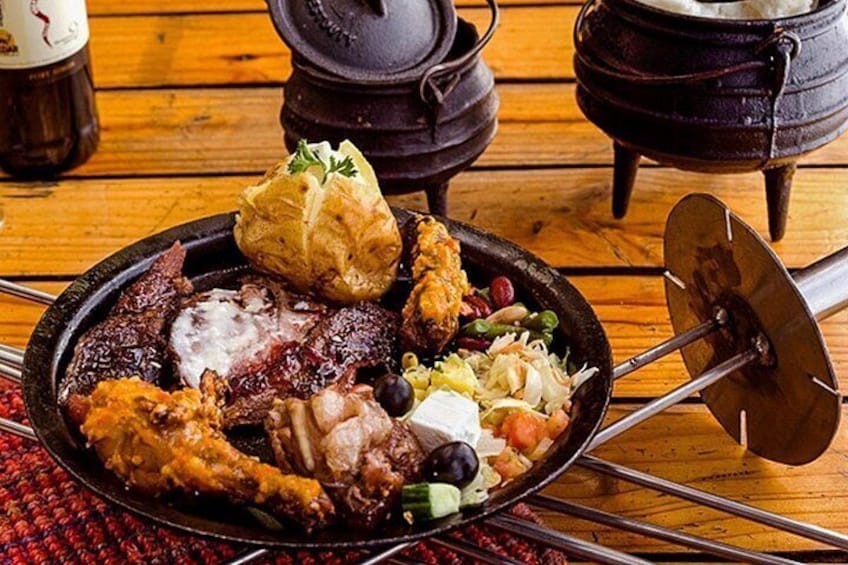 A traditional meal with roasted meats, vegetables, and a pot on a wooden table. 2