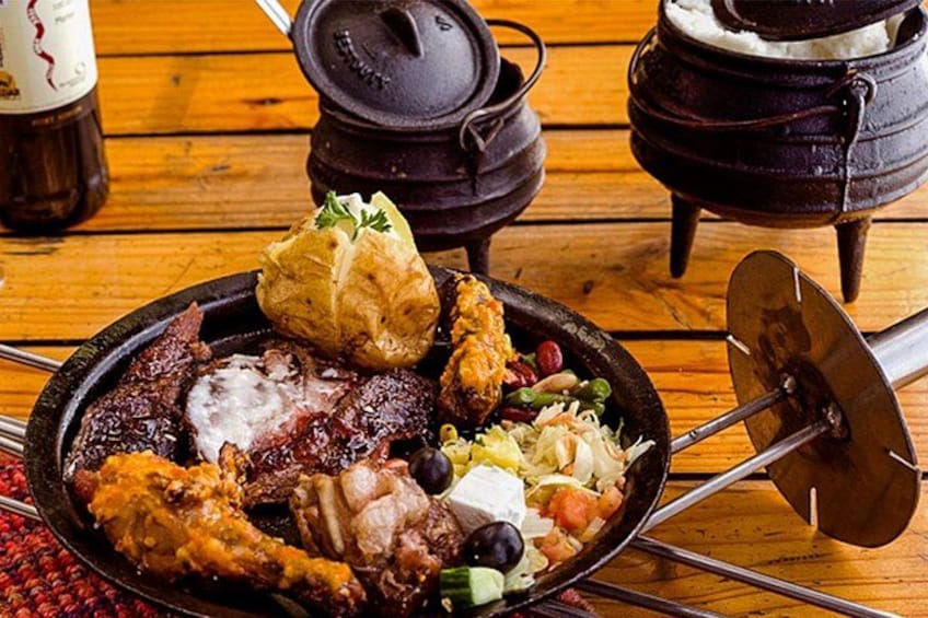 A traditional meal with various meats, a whole roasted chicken, and a side salad on a wooden table. 3