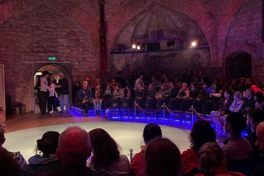 Evento en interior con escenario y público en un edificio histórico de techos abovedados. 4