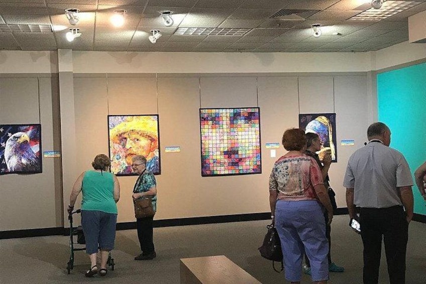 Una galería de arte con gente mirando pinturas. 2