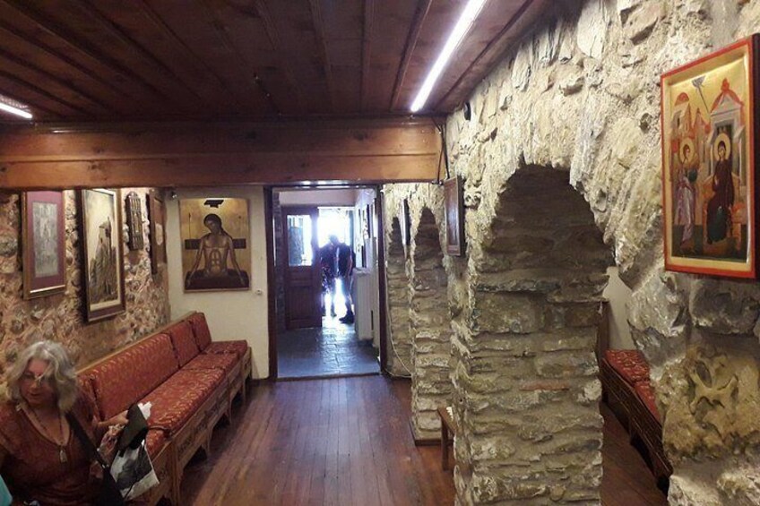 Interior de paredes de piedra con techo de madera, un sofá rojo y un arco de piedra. 5