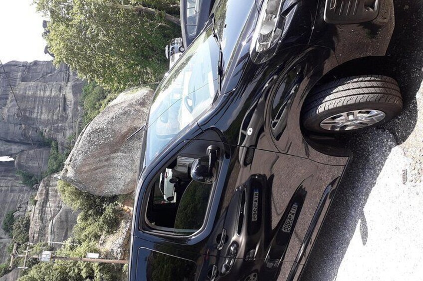 Un coche estacionado en un camino de grava con montañas al fondo. 4