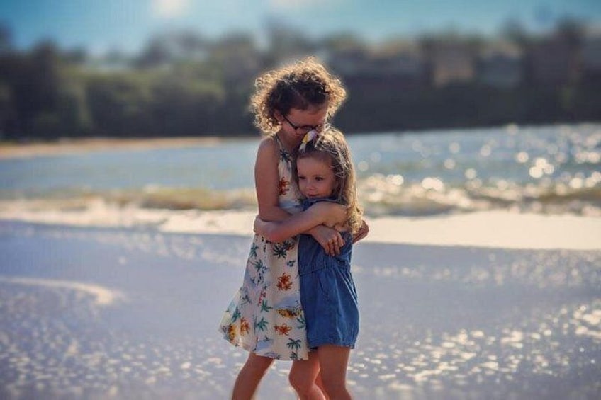 A person holding a child on a beach with water in the background. 5