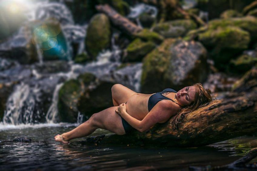 A person lying on a rock by a flowing stream. 4