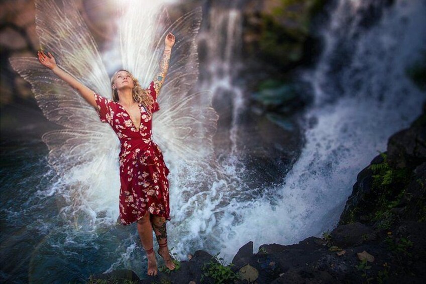 A person with wings standing by a waterfall. 2