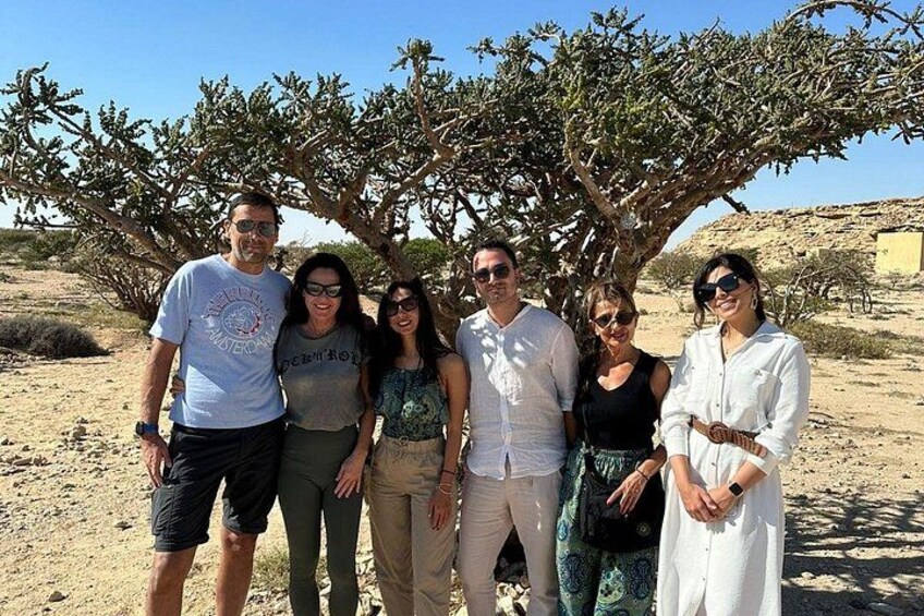 Un groupe de personnes se tient sous un arbre, dans un paysage désertique. 3