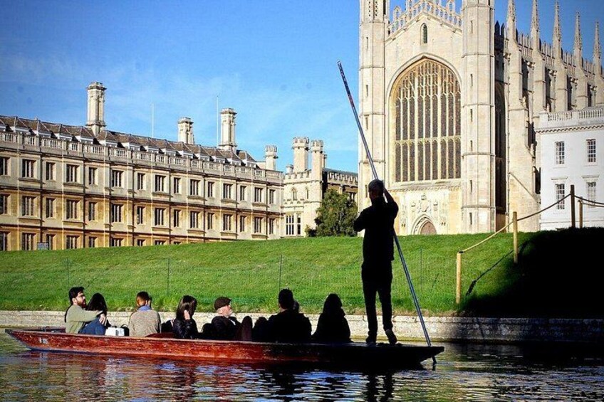 A person rowing a boat with passengers, a river, and a large historic building in the background. 1