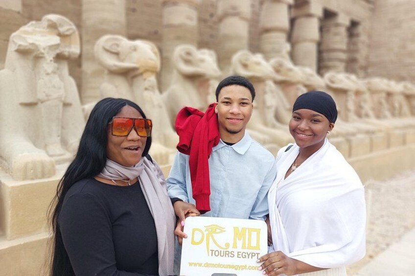 Three people standing in front of ancient Egyptian statues. 1