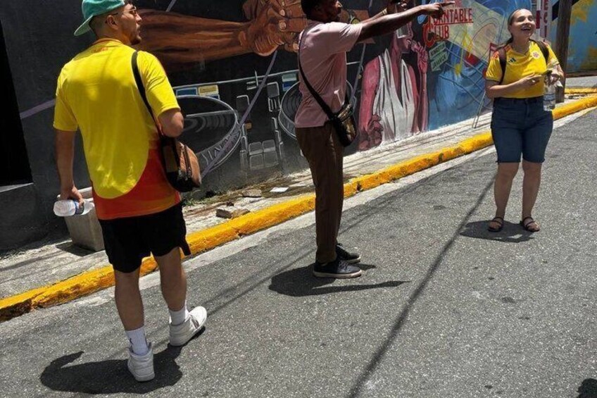 A mural on a wall, a person pointing, and a street. 5