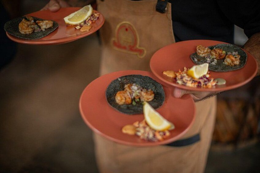 Una persona sosteniendo tres platos de comida, cada uno con una rodaja de limón. 3