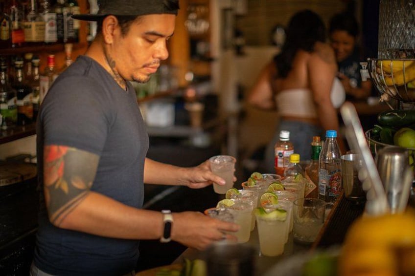 Un cantinero preparando bebidas en una barra con varias botellas y vasos. 3