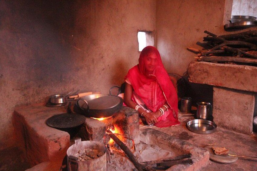 Una persona cocina sobre fuego directo en una cocina rústica, con utensilios y ollas. 1