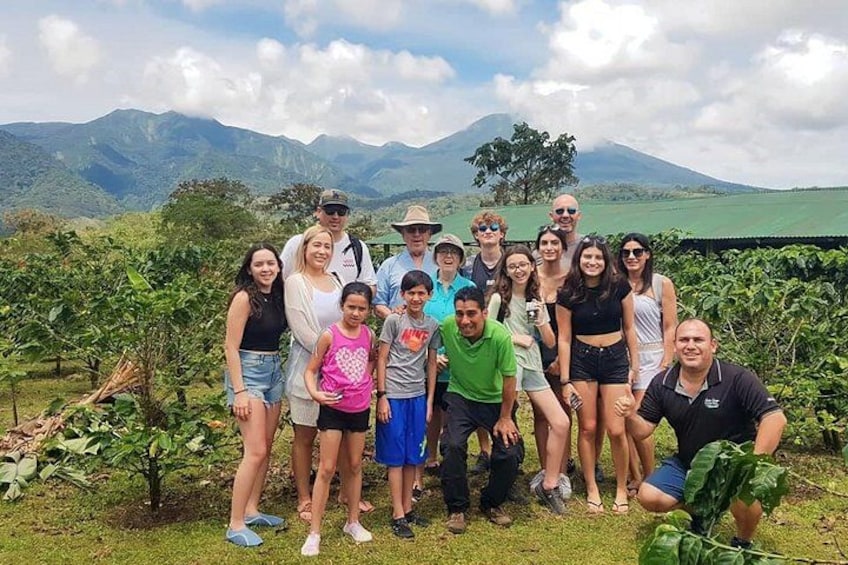 A group of people posing in a vineyard with a mountain in the background. 4