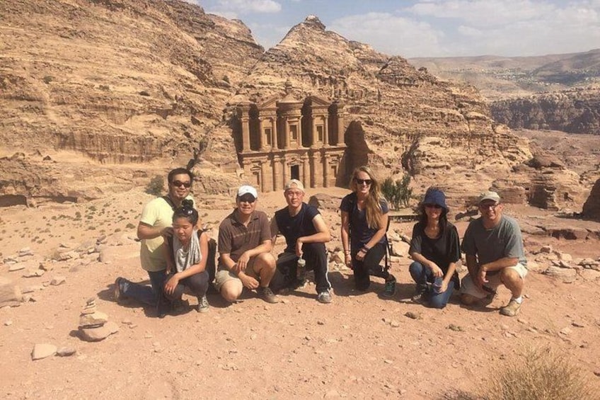 Eine Gruppe von Menschen posiert vor einer großen, uralten Steinarchitektur in einer Wüstenlandschaft. 2