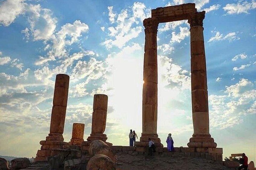Ancient stone columns, a clear sky, and a few people standing around. 4