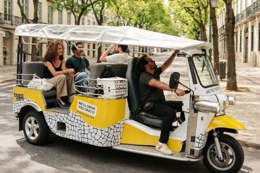 Ein gelb-weißes elektrisches Rikschau mit Fahrgästen, abgestellt auf einer Stadtstraße. 5