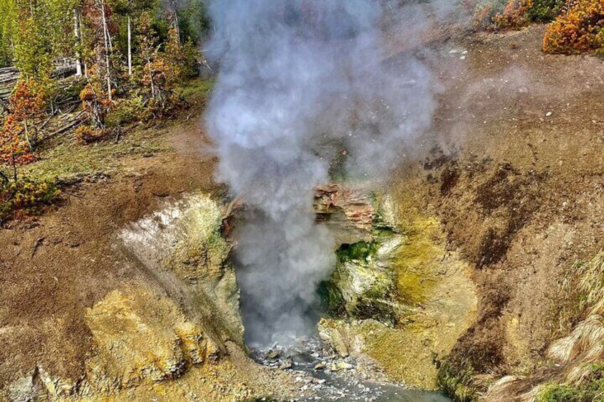 A geothermal area with steam rising from the ground. 2