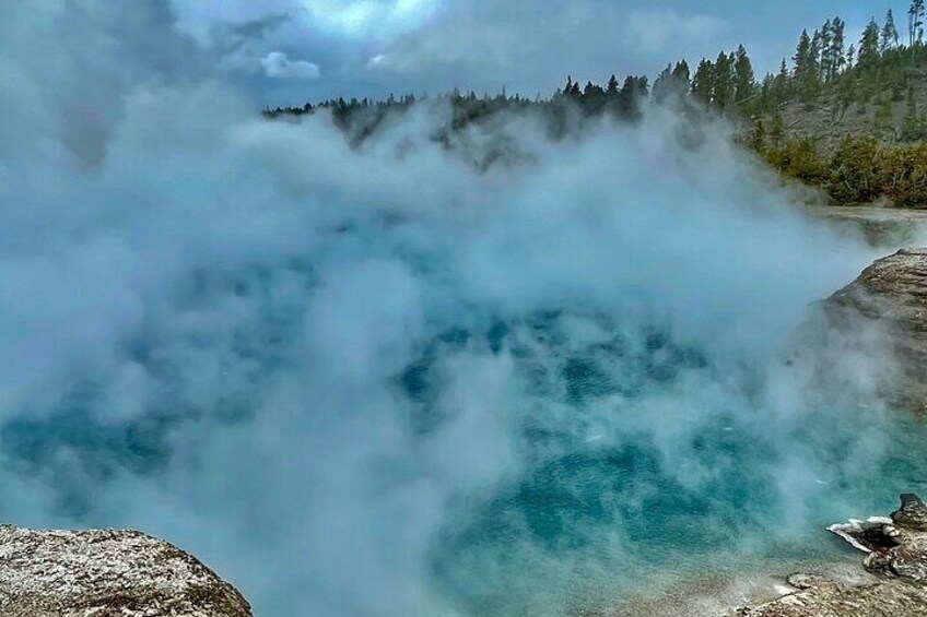 A geyser with steam rising from the water. 3