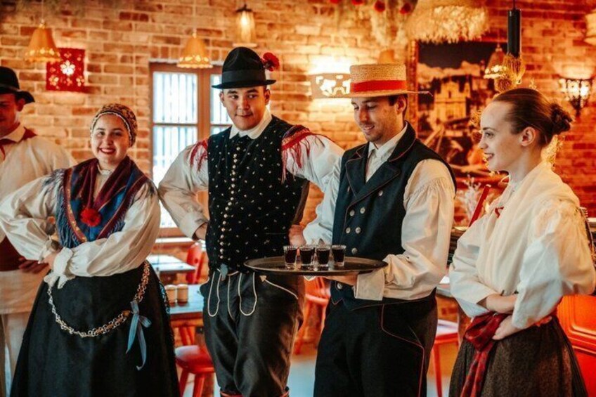 People in traditional attire, a brick wall, and a table with glasses. 3