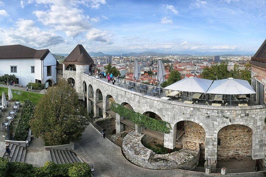 A stone bridge with arches, a white building, and a view of a cityscape in the background. 4